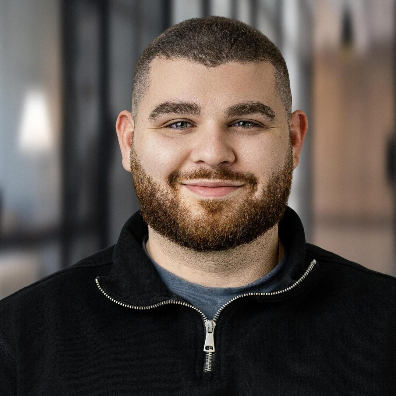 Homme barbu souriant portant un chandail noir à demi-fermeture éclair, portrait d'équipe